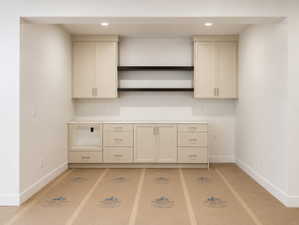 Kitchenette built-in cabinetry with light-toned finishes, a light-toned countertop, and dark wood-finish shelving.