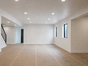Spacious room, recessed ceiling lighting, and two windows with black frames.