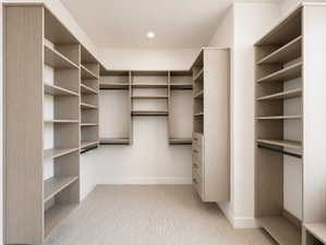Custom closet system featuring extensive wood-finish shelving, multiple hanging rods, built-in drawers, recessed lighting, and soft carpet flooring.