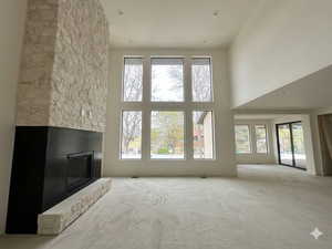 Unfurnished living room featuring a high ceiling, a fireplace, and recessed lighting