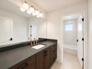 Bathroom vanity featuring a dark countertop with an undermount sink separate from tub/shower area.