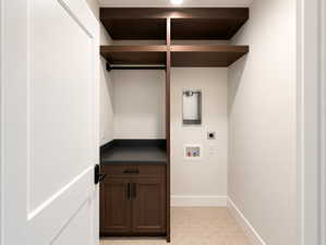 Laundry area featuring built-in wood-finish shelving, a hanging rod, dark cabinetry with dark hardware, a dark countertop, and a light-toned hexagonal floor tile