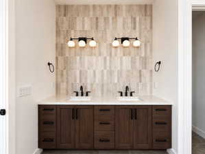 Primary bedroom Dual vanity with wood-finish cabinetry, white countertop, and integrated sinks