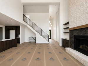 Two-story living area featuring a prominent fireplace with a dark stone surround, a light stone hearth, and a wood mantel