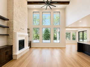 Two-story living area with a stone fireplace, wood-finish flooring, and a beamed ceiling.  Large windows for exterior views and light.