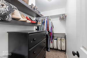 Primary Walk in closet with light colored carpet