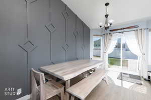 Dining room with hanging lights, a decorative wall, and light wood-style flooring