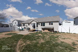 Back of property with a gate, a patio, and a shingled roof