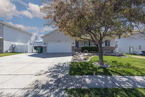 View of front facade featuring a front yard, driveway, brick siding, and an attached garage