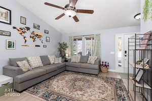 Living area with light wood finished floors, vaulted ceiling, and ceiling fan