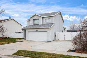 Traditional home featuring a gate, roof with shingles, driveway, and an attached garage