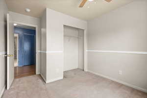Unfurnished bedroom with light carpet, a closet, and ceiling fan