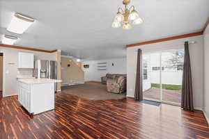 Kitchen with crown molding, open floor plan, light countertops, a center island, and dark wood-style floors