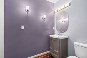 Half bathroom featuring vanity and dark wood-style floors