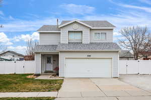 Traditional-style house featuring a gate, a shingled roof, driveway, and a garage