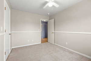 Empty room featuring light colored carpet and ceiling fan