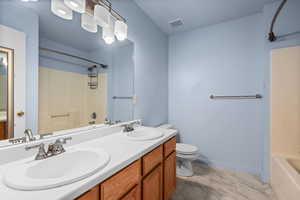 Full bathroom featuring double vanity, bathing tub / shower combination, and light marble finish flooring