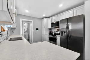 Kitchen with stainless steel appliances, white cabinets, a peninsula, decorative backsplash, and recessed lighting