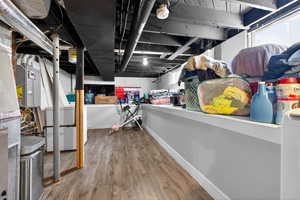 Basement with light wood-style floors, electric panel, and washer / clothes dryer