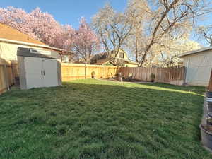 Fenced backyard featuring a storage shed