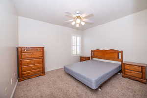 2nd primary suite bedroom featuring light colored carpet, louvered shutters, and ceiling fan. Includes en suite bathroom.