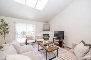 Carpeted living room with skylights, a glass covered fireplace, and a high ceiling