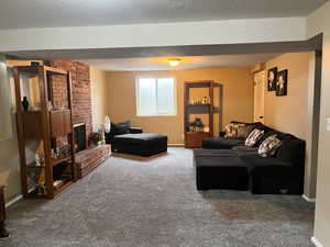Carpeted living room with a brick fireplace and baseboards