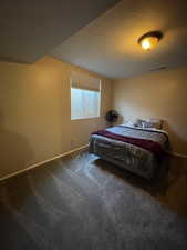 Bedroom with a textured ceiling and dark carpet