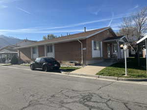 View of front of property featuring brick siding, a front yard, and a mountain view