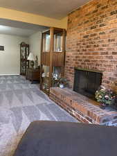 Living room with carpet flooring, a fireplace, and a textured ceiling