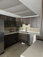 Kitchen with new countertops, stainless steel appliances, dark wood finish cabinetry, and light tile patterned floors
