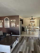 Living area with newer floors, a ceiling fan, and a textured ceiling