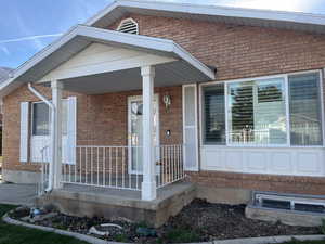 Doorway to property with a porch and brick siding