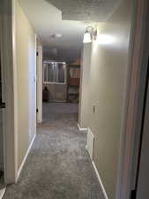 Hall with light carpet and a textured ceiling