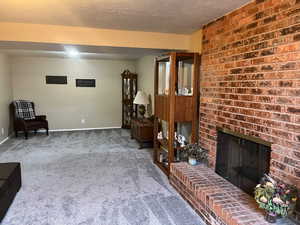 Living area featuring carpet, a fireplace, and a textured ceiling