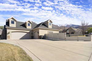 View of front facade with a gate, an attached garage, a shingled roof, stucco siding, and driveway