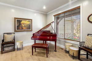 Sitting room with ornamental molding and light wood-style floors