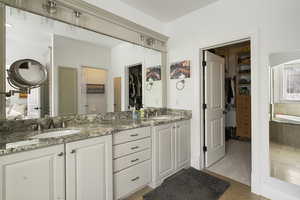 Full bath with a spacious closet, double vanity, a garden tub, and light tile patterned flooring