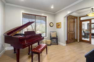 Sitting room with arched walkways, ornamental molding, light wood-style flooring, french doors, and an office area
