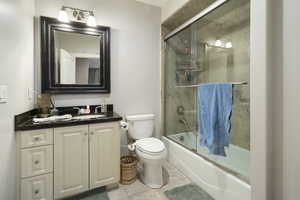 Full bath featuring vanity, shower / bath combination with glass door, and light tile patterned floors