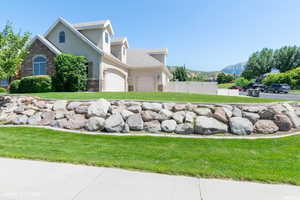 Last Summer - View of side of property with stucco siding, stone siding, and a garage