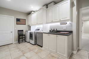 Laundry area featuring cabinet space, independent washer and dryer, and light tile patterned floors