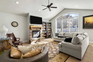 Living area with a stone fireplace, a ceiling fan, wood finished floors, and recessed lighting