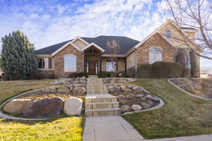 Ranch-style home featuring a front yard, roof with shingles, and brick siding