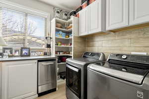 Laundry room featuring cabinet space, separate washer and dryer, and light wood-type flooring