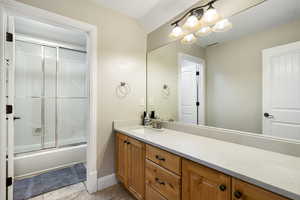 Bathroom featuring vanity, bath / shower combo with glass door, and a textured ceiling