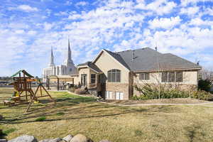 Rear view of property featuring roof with shingles, a yard, and a patio area