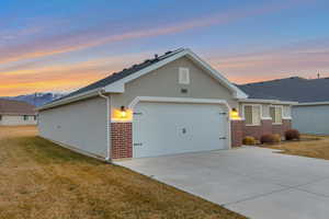 Single story home featuring brick siding, stucco siding, a yard, and an attached garage