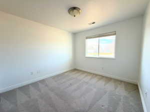 Unfurnished room featuring baseboards and light carpet