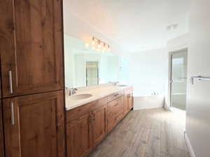 Full bathroom with double vanity, dark wood-type flooring, a bath, and a stall shower